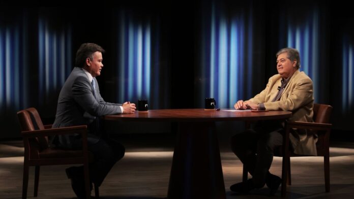 Datena e o promotor Lincoln Gakiya sentados lado a lado em um estúdio de TV durante entrevista.