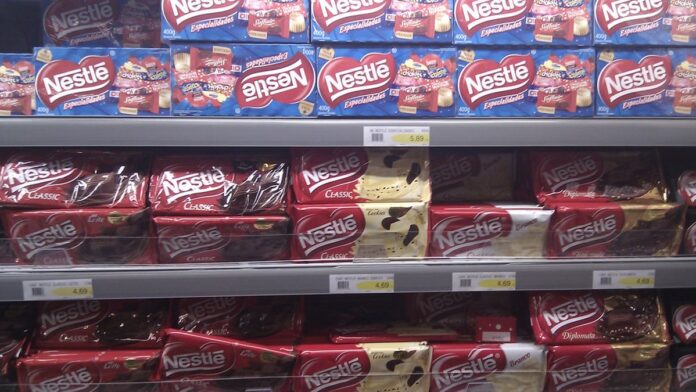 Garrafas de vidro de água mineral Perrier e S.Pellegrino dispostas lado a lado em fundo neutro.