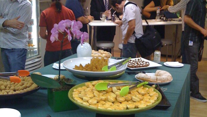 Estudantes usando notebooks em uma sala de aula moderna, focados em telas com códigos de programação.