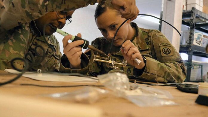 Paraquedistas militares desembarcando de avião em base aérea desértica.
