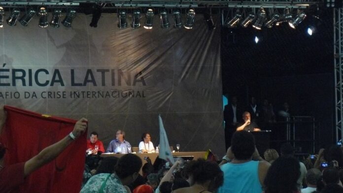 Fotos lado a lado de Lula e Flávio Bolsonaro em fundo neutro, representando disputa eleitoral.