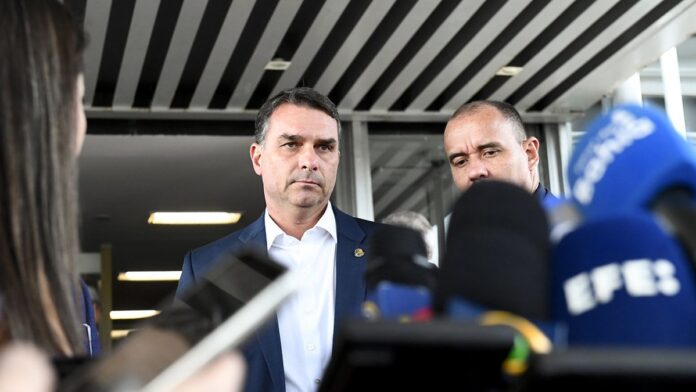 pgr-d-parecer-favor-vel-pris-o-domiciliar-de-jair- Jair Bolsonaro aparece em close, de terno e gravata, falando ao microfone durante evento público.