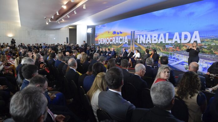 Jair Bolsonaro de terno e gravata, em plano médio, olhando seriamente em direção a uma câmera.