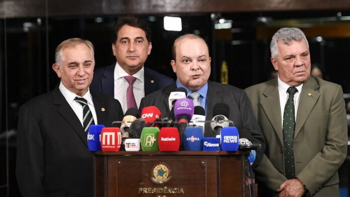 Policial civil fardado conduz um homem algemado para dentro de uma delegacia.