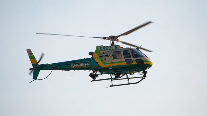 Viaturas policiais com luzes de emergência acesas estacionadas em área desértica sob céu claro.