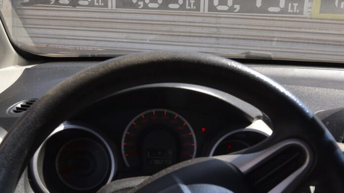 Bomba de combustível em posto de serviço com marcador de preço em destaque.