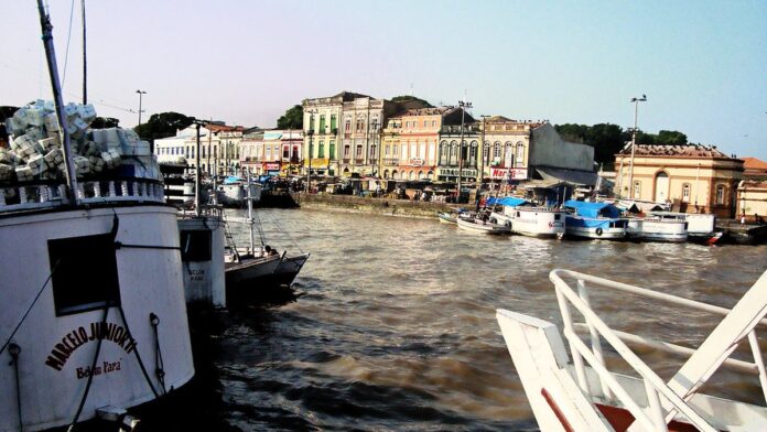 Policiais militares algemam dois suspeitos sentados no chão de uma rua, sob luz do dia, em área urbana de Belém.