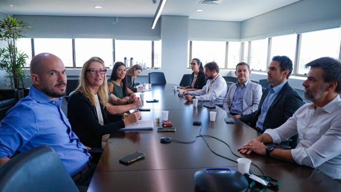 Vista aérea do Guaíba com vegetação nas margens e técnicos analisando dados ambientais em um tablet.