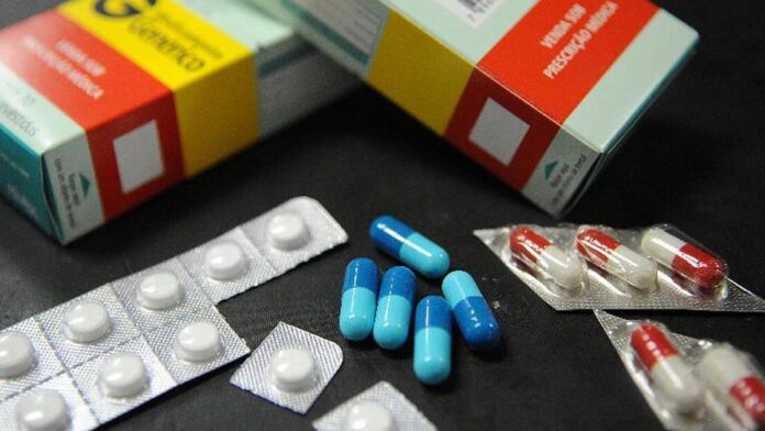 Caixa de medicamentos em destaque sobre uma mesa, simbolizando o impacto econômico dos preços para o consumidor.