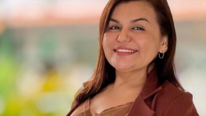 Canoa de madeira navegando em rio sinuoso na floresta amazônica, com vegetação densa nas margens sob céu nublado.