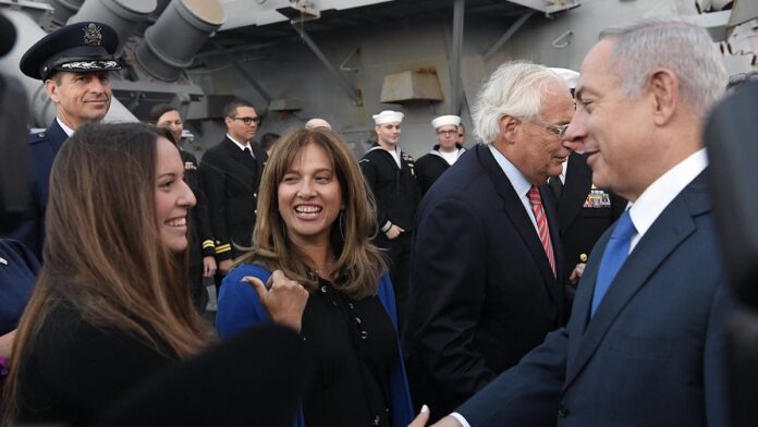 Ross Friedman toca guitarra elétrica em um show, usando jaqueta de couro e expressão focada sob luzes de palco.