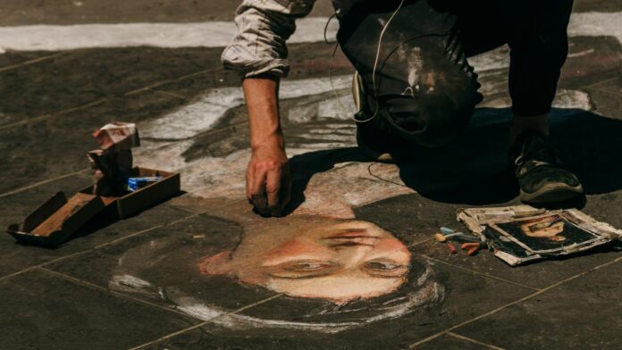 Street artist creating a detailed chalk portrait on the pavement in Florence, Italy.