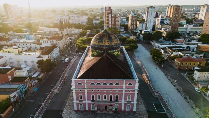 Aerial view of the iconic Teatro Amazonas in Manaus, Brazil, bathed in warm sunset light.