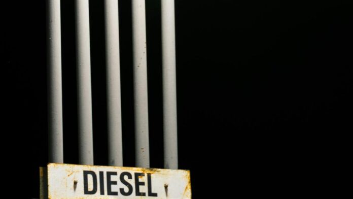 Diesel fuel sign on metal pipes against a dark black background at night.