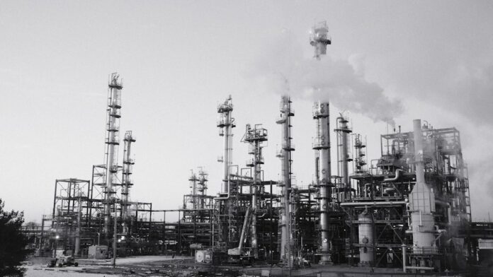 Industrial refinery with smoking stacks under a cloudy sky