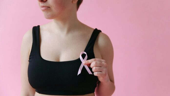 Close-up of a woman holding a pink ribbon symbolizing breast cancer awareness.