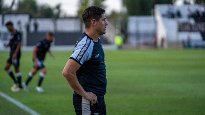 Soccer coach observing match strategy during an outdoor game.