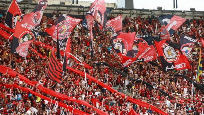 Fans passionately cheer with flags at a football match in Maracanã Stadium, Rio de Janeiro.