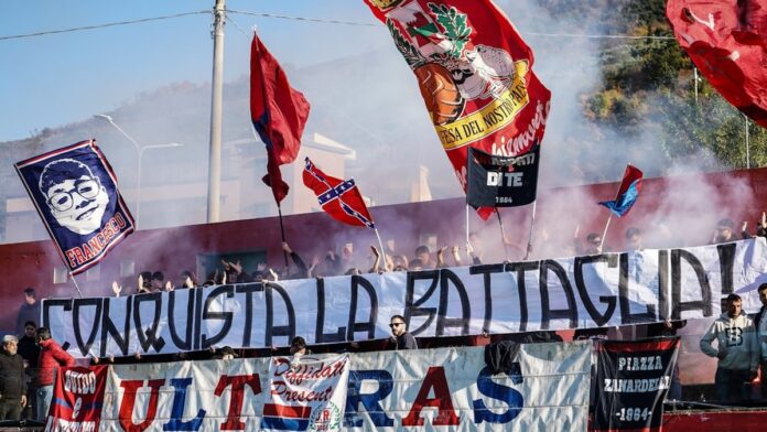 Fans wave flags and banners at a sporting event.