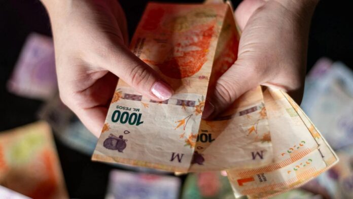 Hands holding Argentine peso banknotes, showcasing currency details in Buenos Aires.