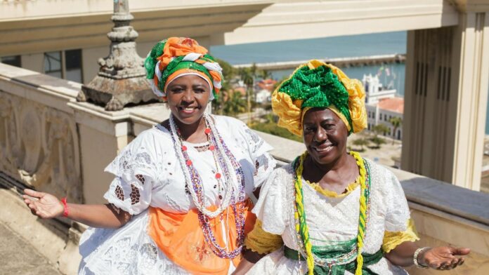 Two Afro-Brazilian women in vibrant traditional clothing posing outdoors in Salvador, Brazil.