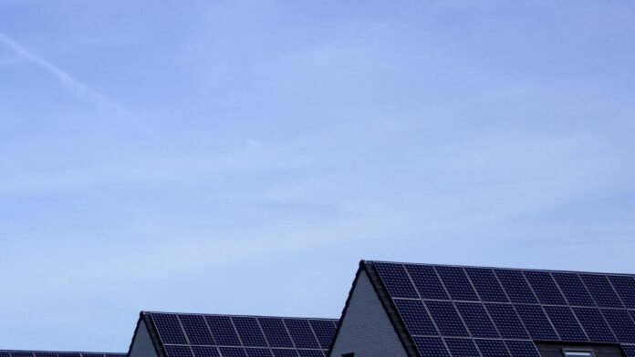 Modern Belgian houses with solar panels on rooftops under a clear blue sky.