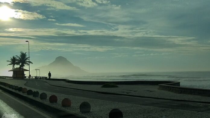 Grupo de voluntários com coletes de identificação recolhendo resíduos nas margens de um rio arborizado no Paraná.