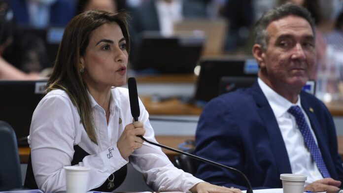 Fachada de prédio residencial com varandas e grades, sob céu nublado, em perspectiva de baixo para cima.