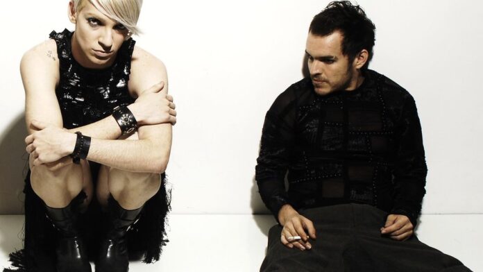 Pessoas costuram roupas em oficina de upcycling com tecidos diversos em um ambiente colaborativo iluminado.