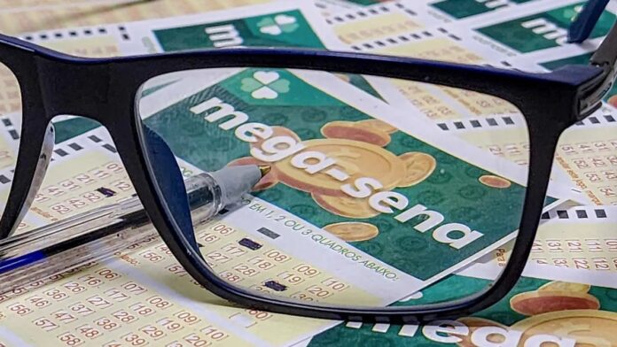 uma-aposta-acerta-sozinha-os-seis-n-meros-e-fatura Mão segurando um volante de apostas da Mega-Sena preenchido em uma casa lotérica.