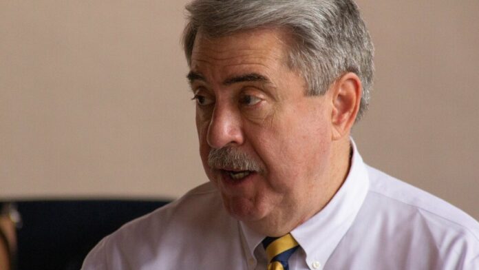 Vista aérea de uma floresta densa com uma estrada de terra estreita cortando a vegetação, sob céu limpo.