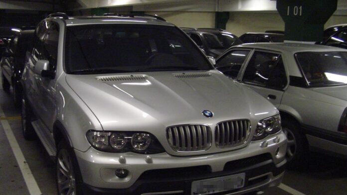 venda-de-carros-eletrificados-cresce-65-5-no-brasi Carro elétrico moderno sendo carregado em um posto de recarga público, exibindo painel luminoso de energia.