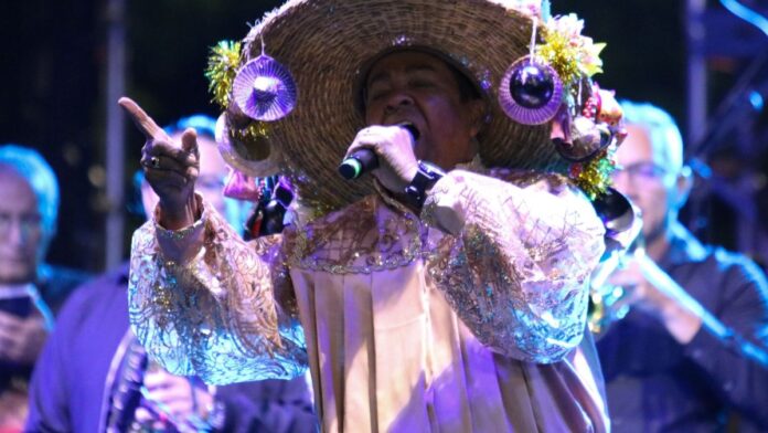 Palco iluminado durante show na Virada Cultural, com grande público e luzes coloridas refletindo na multidão à noite.