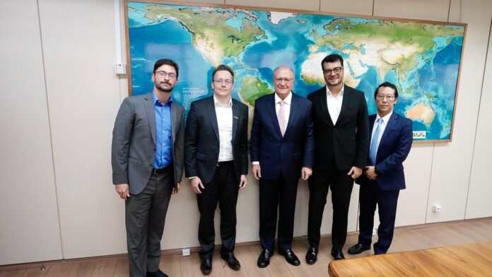 Foto de um escritório moderno com um smartphone exibindo o logo da Wellhub e gráficos de crescimento ao fundo.