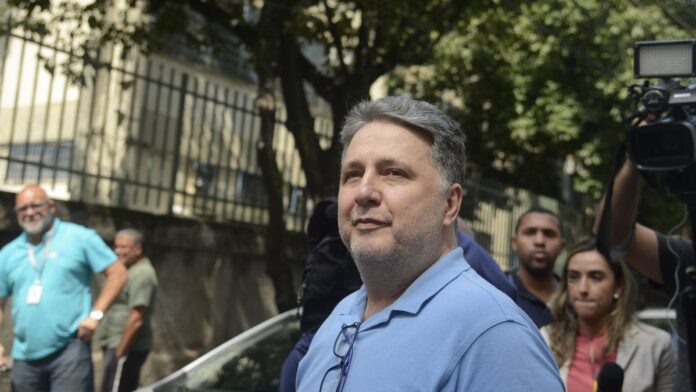 Anthony Garotinho de terno e gravata, em plano médio, olhando para frente em ambiente de tribunal ou entrevista.