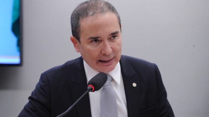 Profissional de educação física orienta idoso em aparelho de musculação dentro de uma academia.