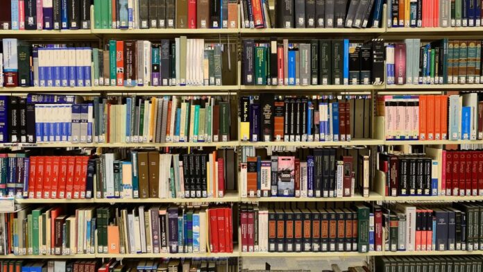 Smartphone exibindo a interface do aplicativo MEC Livros com uma estante virtual de obras literárias na tela.