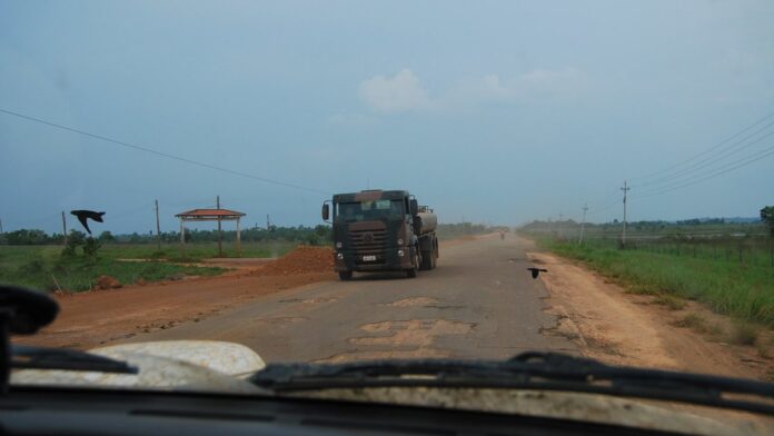 br-319-na-amaz-nia-governo-federal-aprova-obras-se Trecho de estrada de terra cercado por densa floresta amazônica sob céu nublado.