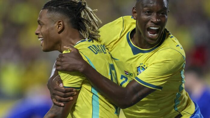 brasil-vence-a-cro-cia-por-3-a-1-antes-da-convoca- Jogadores da seleção brasileira celebram um gol abraçados no gramado, vestindo o uniforme amarelo oficial.