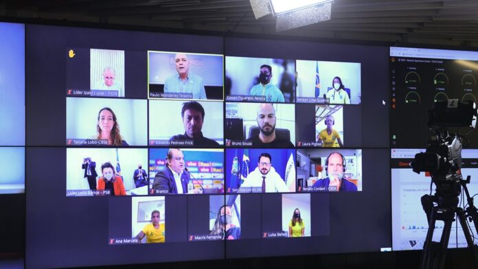 Jogador de vôlei Bruninho salta e estica o braço para realizar uma defesa baixa durante partida da Superliga.