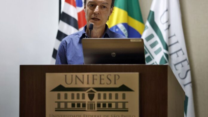 Fotografia de manifestantes segurando fotos de pessoas desaparecidas em uma praça pública, pedindo por justiça.