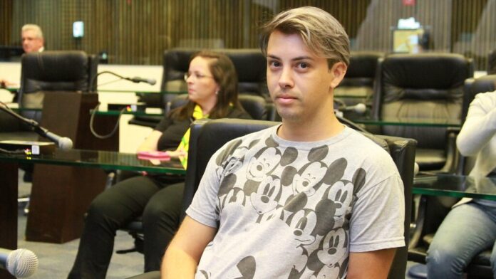 Fachada da Câmara Municipal de Apucarana com bandeiras e pedestres circulando em frente ao prédio público.