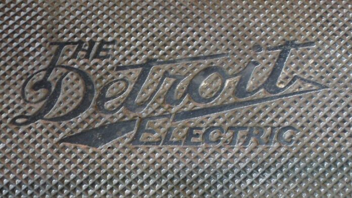 Carro elétrico moderno parado em uma estação de carregamento pública sob luz do dia.