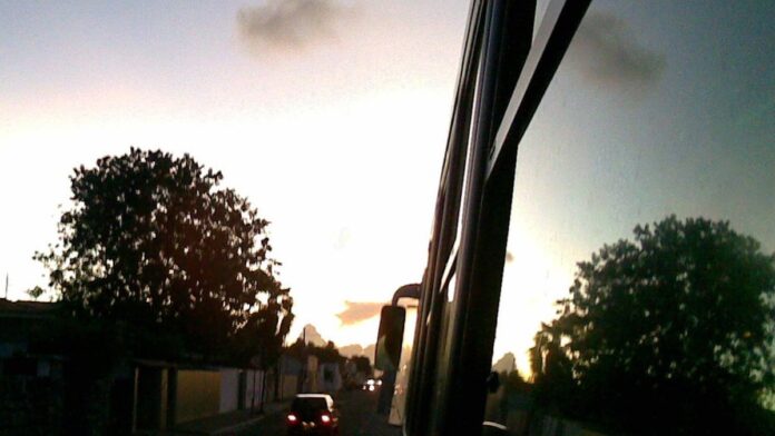 Dois homens algemados são escoltados por policiais civis em frente a uma delegacia de polícia.