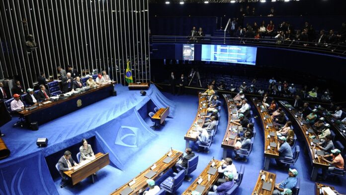 coritiba-defende-volante-willian-oliveira-ap-s-vai Volante do Coritiba corre no gramado durante partida de futebol, olhando para a arquibancada com expressão séria.
