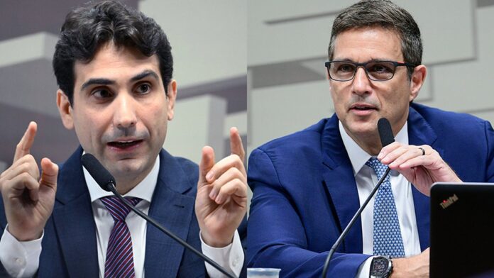 Galípolo e Campos Neto sentados lado a lado em uma mesa durante audiência no Senado, com microfones à frente.