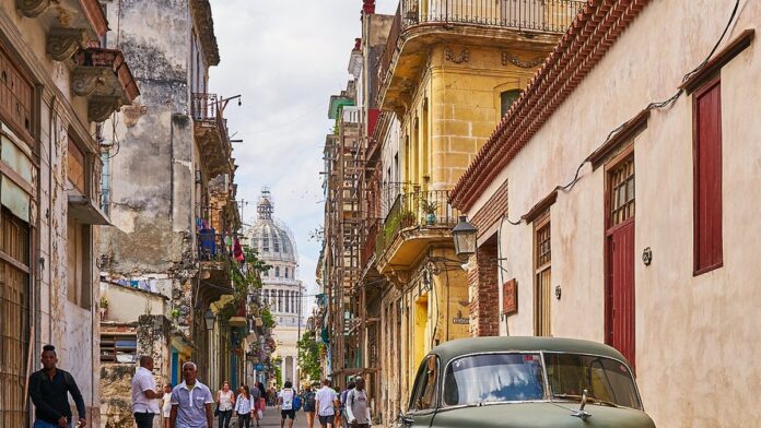 Homens e mulheres deixam o portão de uma prisão cubana, sendo recebidos por familiares com abraços e emoção.
