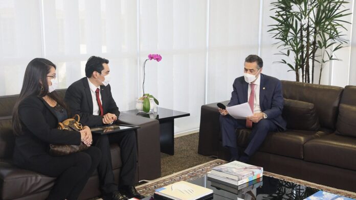 Pessoa preenchendo formulário de título de eleitor em um cartório eleitoral com computadores ao fundo.