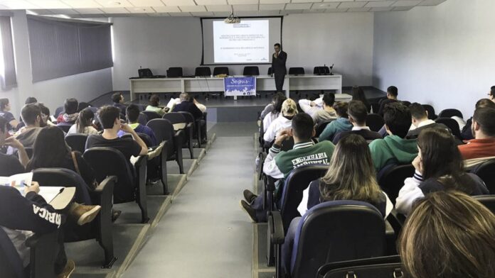 Representantes sentados em mesa de reunião, em uma sala, discutindo documentos sobre um mapa de bacias hidrográficas.