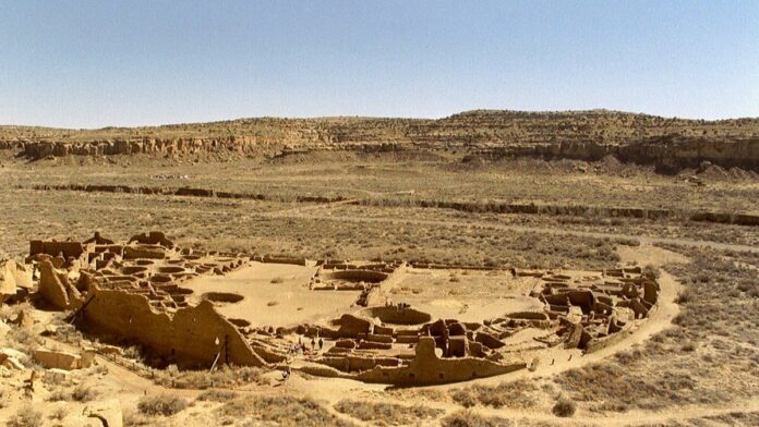 Vista aérea de sondas de perfuração de petróleo instaladas em uma paisagem árida e rochosa no Chaco Canyon.